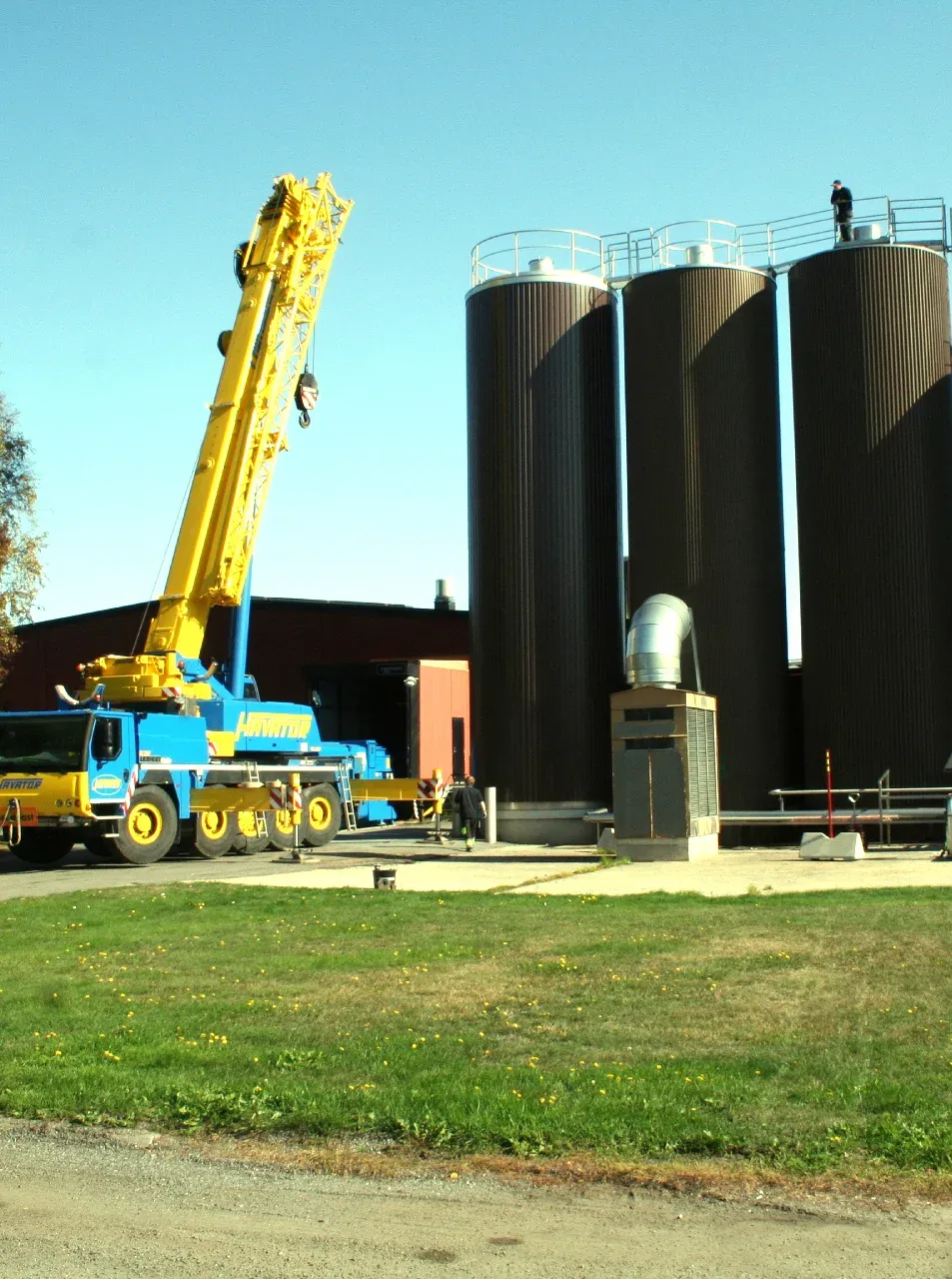 Mobilkran vid tre silotankar under montage utanför en livsmedelsfabrik